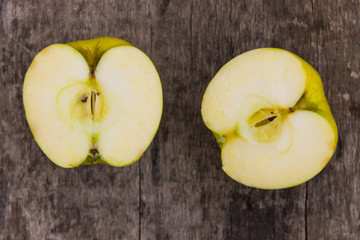 Halves of green apple on rustic wooden table