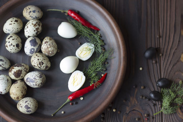 Obraz na płótnie Canvas quail eggs, olives, chili and spices on a wooden table