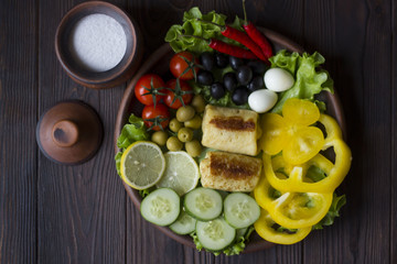 pancakes and fresh organic vegetables: tomatoes, peppers, parsley, lemon, cucumber, chili, spices and olives in a clay plate on the table dark wood