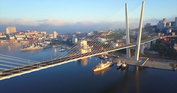 Panoramic aerial view of impressive Golden Bridge (cable-stayed, built in 2012) across the Golden Horn harbour and morning Vladivostok city is on the background. Russia. Autumn