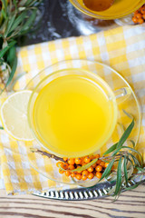 Tea made from sea buckthorn berries healthy for health delicious, saturated with vitamins surrounded by berries and sea buckthorn leaves and maintaining health in the body top view