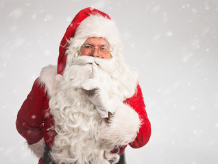 Santa Claus making a silence gesture, on snowy background 