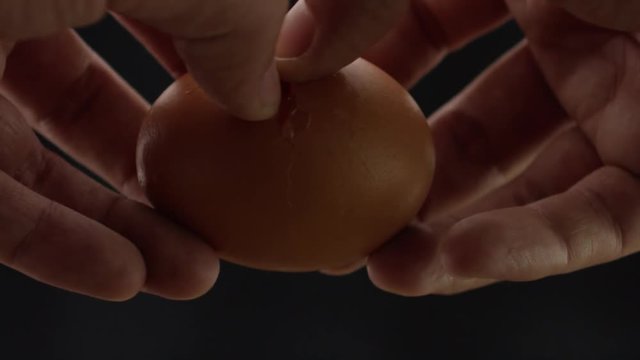 hands breaks the egg, yolk and protein flows out of the egg, frame close-up and slow-motion frame