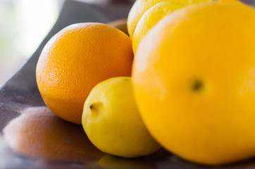 Orange lemon grapefruit in metal dish on the wooden table daylight