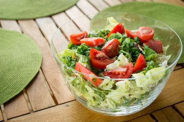 Vegetable salad in the glass bowl on the wooden table