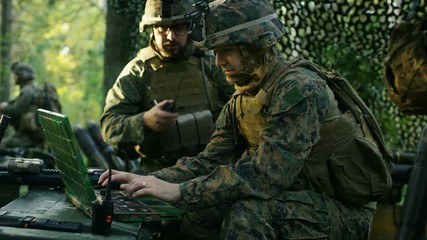 Military Staging Base, Officer Gives Orders to Chief Engineer, They Use Radio and Army Grade Laptop. They're in Camouflaged Tent in a Forest. They're on Reconnaissance Operation/ Mission. - Powered by Adobe