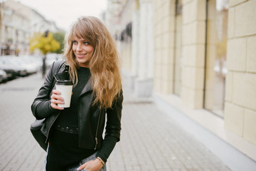 Portrait of a beautiful girl on the street, holding a paper cup