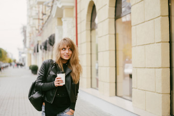 Portrait of a beautiful girl on the street, holding a paper cup