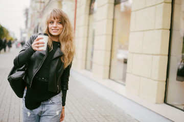 Portrait of a beautiful girl on the street, holding a paper cup
