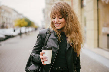 Portrait of a beautiful girl on the street, holding a paper cup