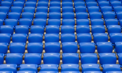 Naklejka premium Rows of blue plastic armchairs on a tribune of stadium.
