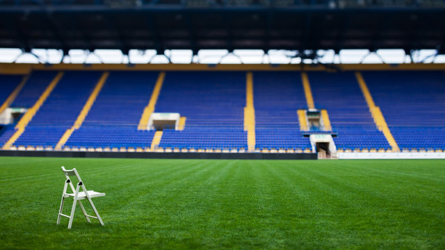 The lonely white chair on the field of stadium.
