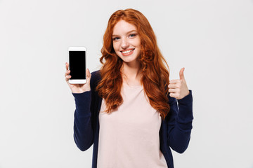 Fototapeta premium Happy young redhead lady showing display of mobile phone