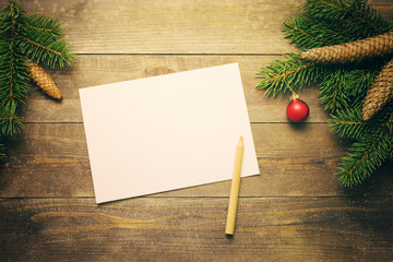 Empty clean sheet of paper for your text, wooden pencil and christmas fir tree on wooden background, top view. Christmas background