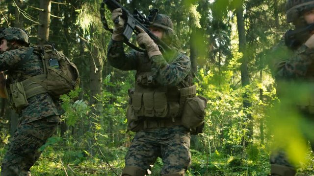 Three Fully Equipped Soldiers Wearing Camouflage Uniform Attacking Enemy, They Stop in Shooting Ready Stance, Aiming Rifles. 