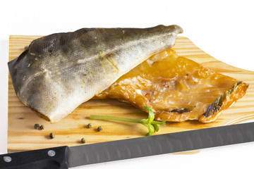 Différents poissons fumés sur une planche à découper sur fond blanc