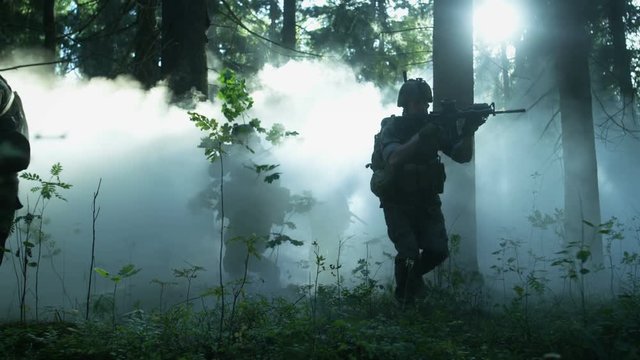 Fully Equipped Soldiers Wearing Camouflage Uniform Attacking Enemy, Rifles Ready to Shoot. Military Operation in Action, Squad Running in Formation Through Dense Smokey Forest. 