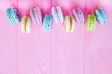 Tasty colorful macaroons in pink background. Text space. Pastel colors.