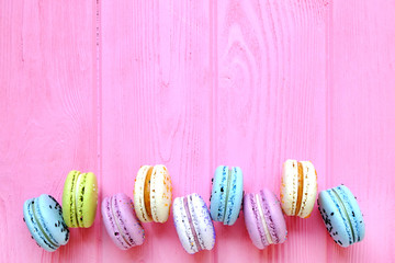 Tasty colorful macaroons in pink background. Text space. Pastel colors.