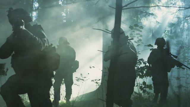 Fully Equipped Soldiers Wearing Camouflage Uniform Attacking Enemy, Rifles Ready to Shoot. Military Operation in Action, Squad Running in Formation Through Dense Smokey Forest. Slow Motion. 