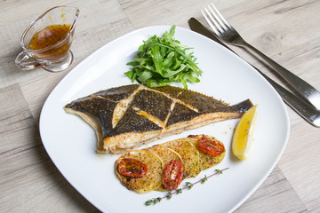Fried flounder with zucchini, tomatoes and arugula. Close-up, selective focus.