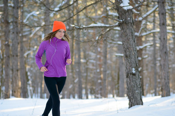 Young Woman Running in Beautiful Winter Forest at Sunny Frosty Day. Active Lifestyle Concept.