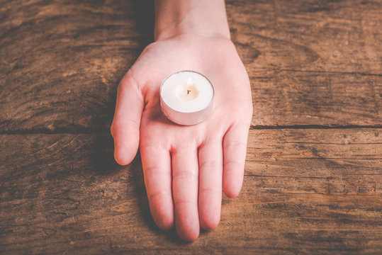 hands that offer the flame of a candle