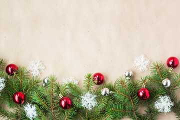 Festive christmas border with red and silver balls on fir branches and snowflakes on rustic beige background