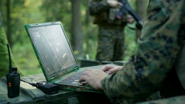 Military Operation in Action, Soldiers Using Military Grade Laptop Targeting Enemy with Satellite. In the Background Camouflaged Tent on the Forest. Shot on RED EPIC-W 8K Helium Cinema Camera.