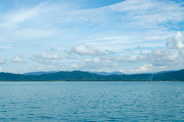 Horizontal of Seascape including Forest Mountain, Blue Sky and Wave of Water Foam in Ocean.