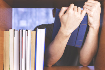 Young man looking for a book on a shelf