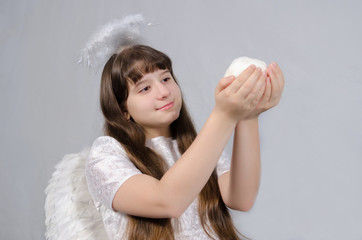 girl in an angel costume holds a snowball