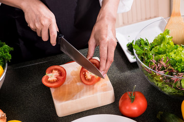 Healthy Woman makes fresh vegetable salad with olive oil, tomato and salad.