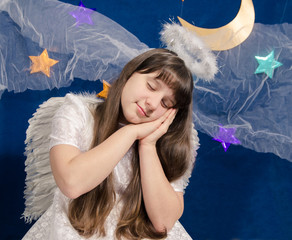 girl in angel costume sleeps on a background of dark blue sky