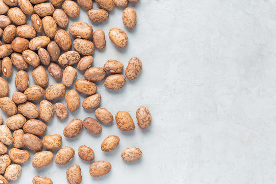 Uncooked dry pinto beans on a gray concrete background, top view, copy space
