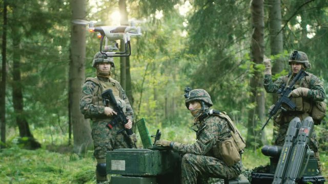 In the Military Staging Base Army Engineer and Soldiers Fly Military Grade Industrial Drone for their Reconnaisance/ Surveillance Mission/ Operation. Theater of Operation is in Forest Area. 