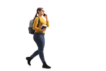 Female teenage student walking and talking on a phone