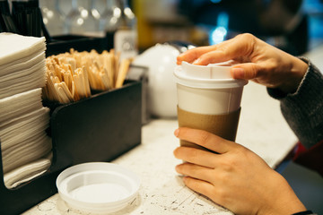 womans hand near rack with cup of coffee