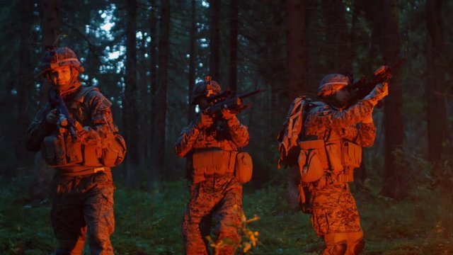 Squad of Five Fully Equipped Soldiers in Camouflage on a Reconnaissance Military Night Mission. They're Lit by Red Flare and Move Through Dense Forest. Shot on RED EPIC-W 8K Helium Cinema Camera.