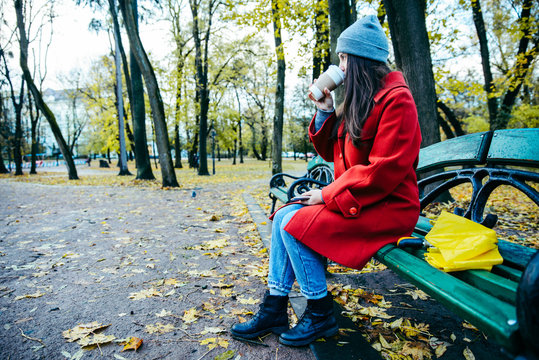 woman on the bench in park with umbrella and cup of coffe