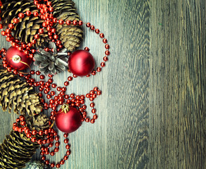 Naklejka premium Christmas balls, cones and ornaments on wooden background. 