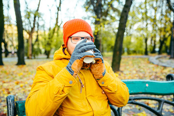 young man drinking hot coffee outdoors in cold autumn day