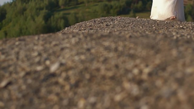 The sensitive walk of the woman in white long boho dress in the sunny mountains during holidays