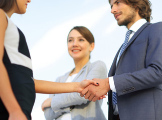 Businesspeople  shaking hands against room with large window loo