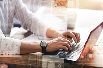 Fast typist. The close up of beautiful male hands typing on the keyboard of a crimson laptop while...