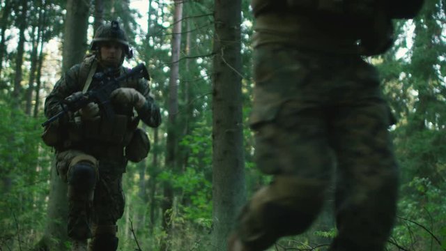 Fully Equipped Soldiers Wearing Camouflage Uniform Attacking Enemy, Rifles Ready to Shoot. Military Operation in Action, Squad Running in Formation Through Dense Smokey Forest. Slow Motion. 