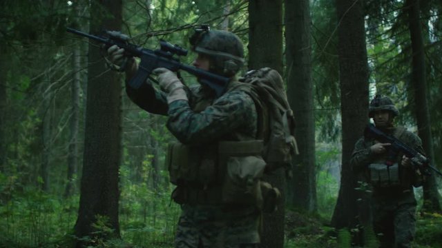 Fully Equipped Soldiers Wearing Camouflage Uniform Attacking Enemy, Rifles Ready to Shoot. Military Operation in Action, Squad Walking in Formation Through Dense Forest. Following Shot. 