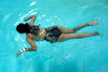Young woman swimming underwater in the swimming pool
