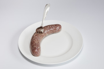 Frische rohe Bratwurst auf einem weißen Teller