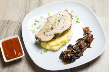 Baked pork with mashed potatoes, fried mushrooms and tomato sauce. Close-up, selective focus.